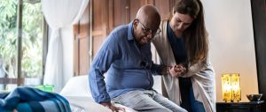 Elderly man assisted to get out of bed
