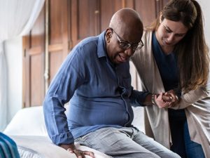 Elderly man assisted to get out of bed